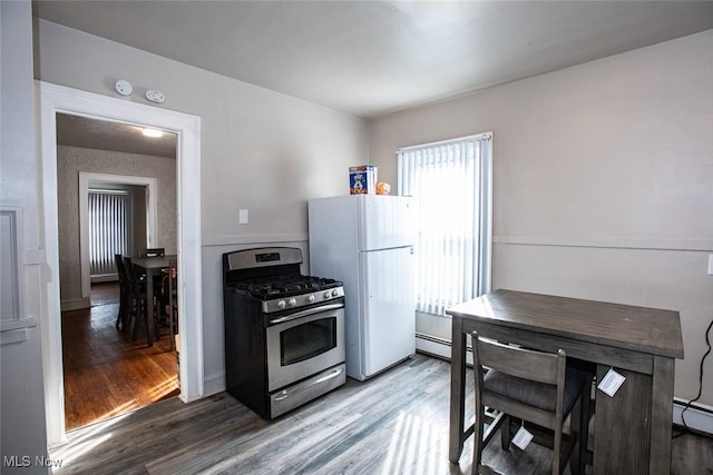 kitchen featuring a baseboard heating unit, hardwood / wood-style floors, stainless steel range with gas stovetop, and white refrigerator