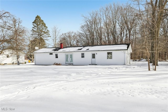 snow covered back of property featuring french doors