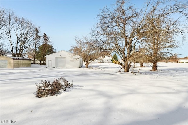 yard layered in snow with an outbuilding and a garage