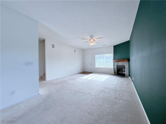 unfurnished living room featuring ceiling fan, a fireplace, light carpet, and a textured ceiling