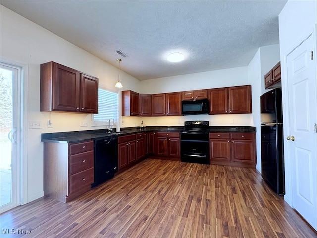 kitchen with sink, hanging light fixtures, dark hardwood / wood-style floors, black appliances, and a textured ceiling