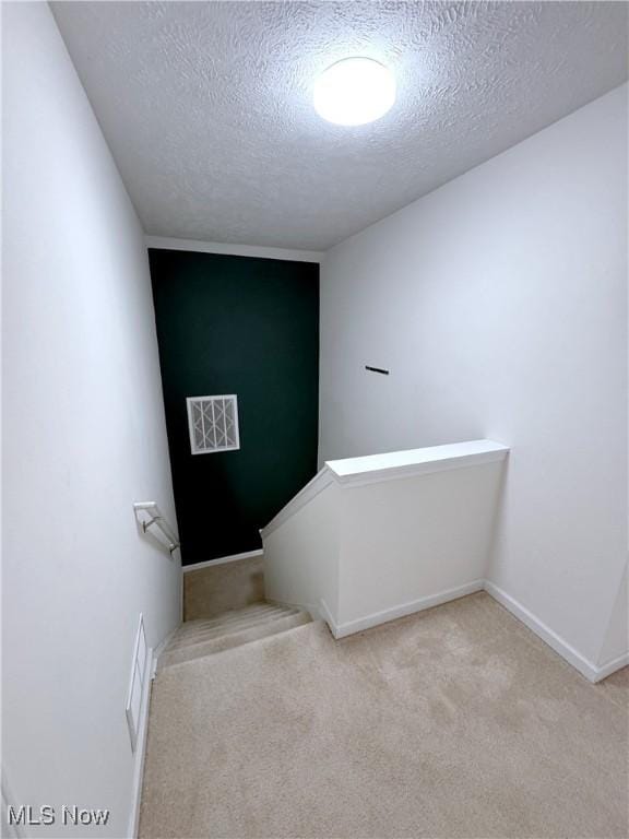 staircase with carpet floors and a textured ceiling