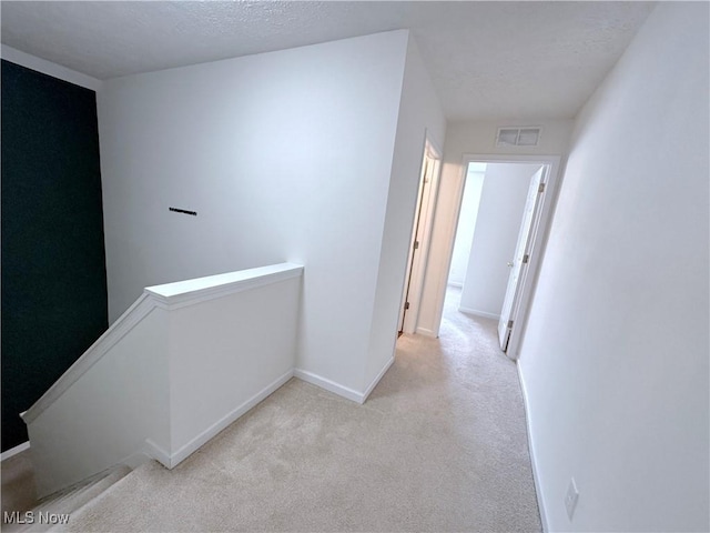 hall with light carpet and a textured ceiling