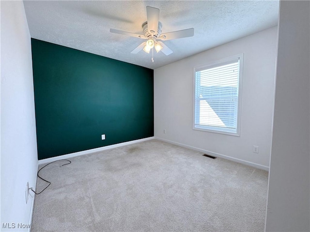 carpeted empty room with ceiling fan and a textured ceiling