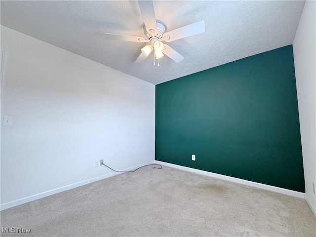 carpeted spare room with a textured ceiling and ceiling fan