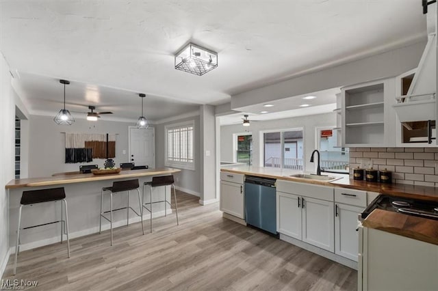 kitchen with white cabinetry, stainless steel dishwasher, sink, and butcher block countertops