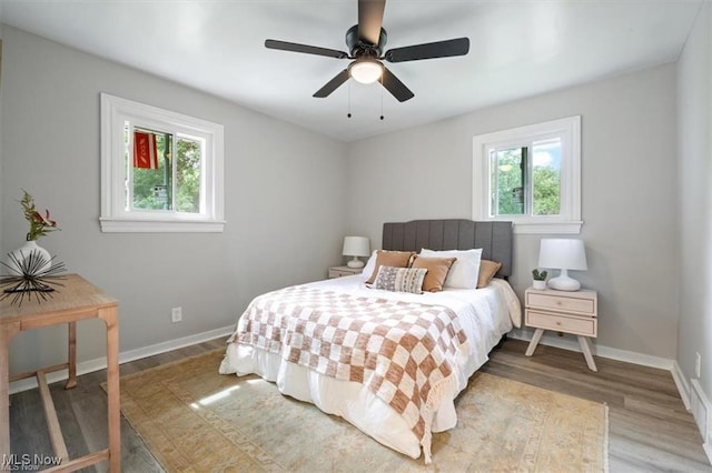 bedroom with hardwood / wood-style flooring, ceiling fan, and multiple windows