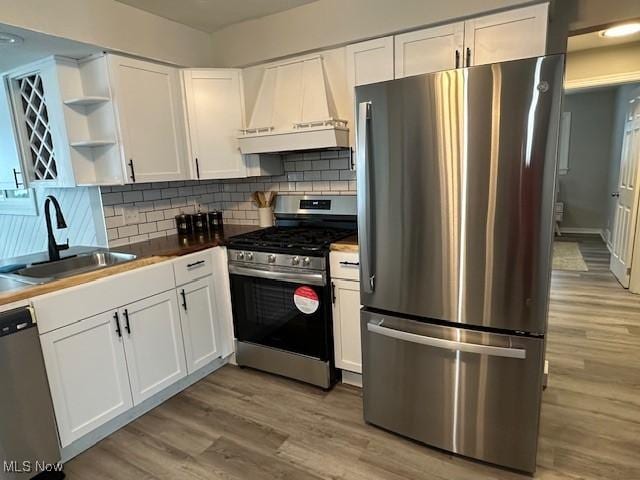 kitchen with white cabinetry, premium range hood, appliances with stainless steel finishes, and sink