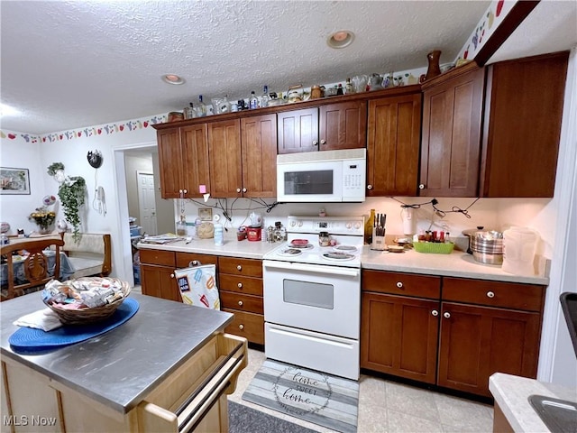 kitchen featuring a textured ceiling, white appliances, and light tile patterned floors