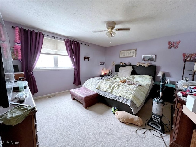 carpeted bedroom featuring ceiling fan and a textured ceiling