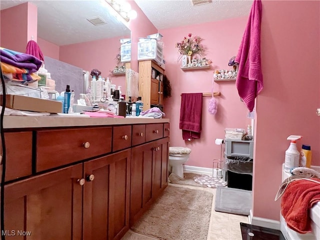 bathroom with vanity, toilet, and a textured ceiling