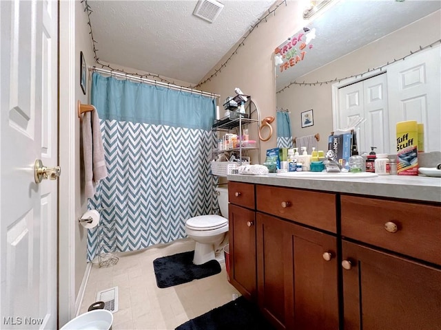 bathroom with toilet, vanity, a textured ceiling, and walk in shower