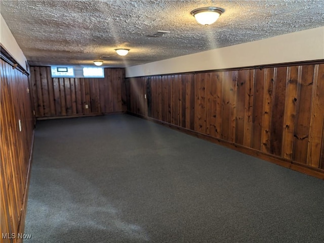 basement featuring wooden walls and a textured ceiling