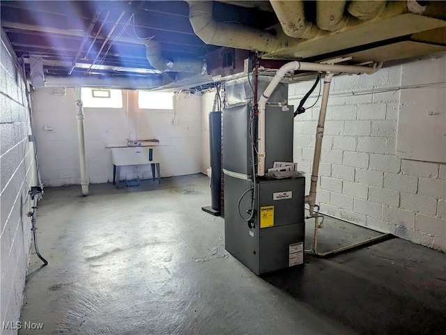 basement featuring heating unit, sink, and water heater