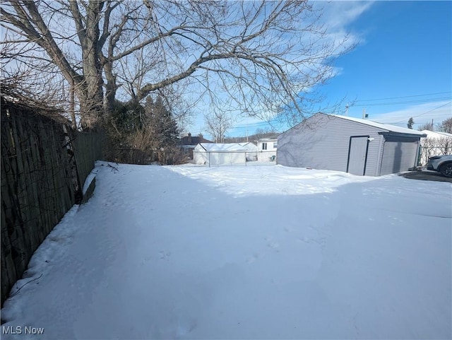 yard layered in snow with a garage and an outdoor structure