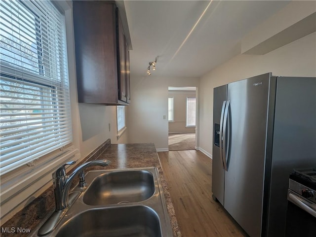 kitchen featuring hardwood / wood-style floors, sink, oven, stainless steel fridge, and dark brown cabinets