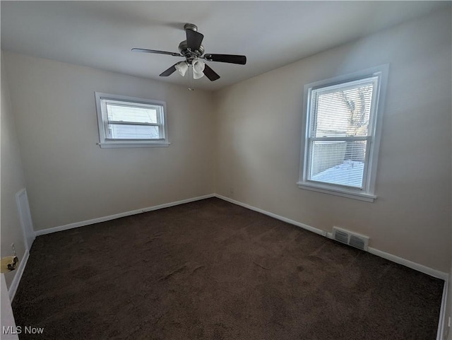 spare room with dark colored carpet and ceiling fan