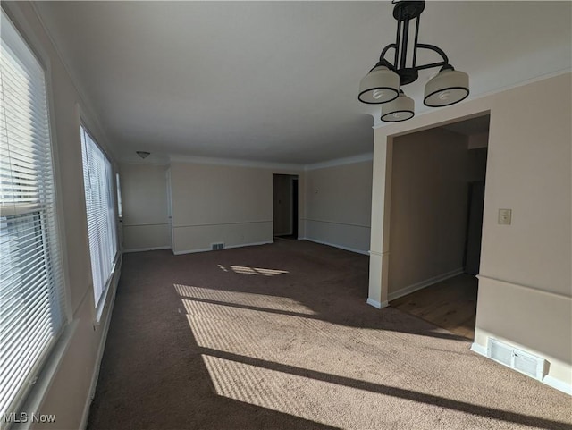 interior space with crown molding, a chandelier, and dark carpet