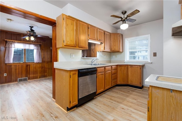 kitchen with sink, stainless steel dishwasher, wooden walls, and light wood-type flooring