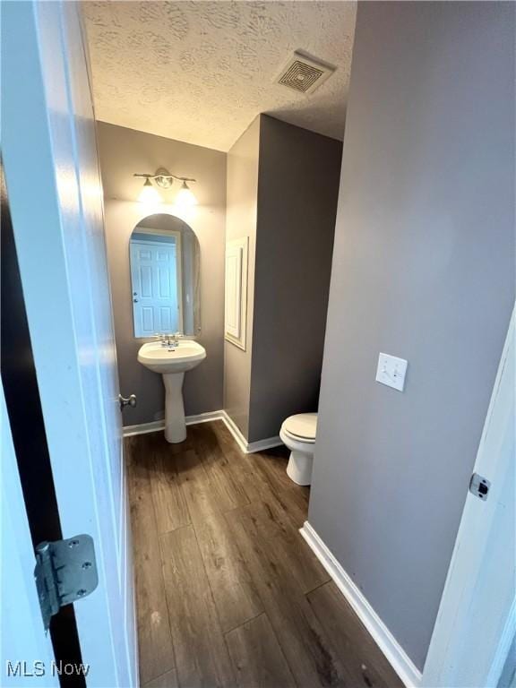 bathroom featuring sink, toilet, hardwood / wood-style floors, and a textured ceiling