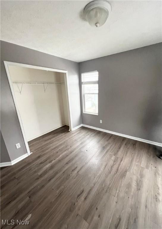 unfurnished bedroom with dark hardwood / wood-style floors and a closet