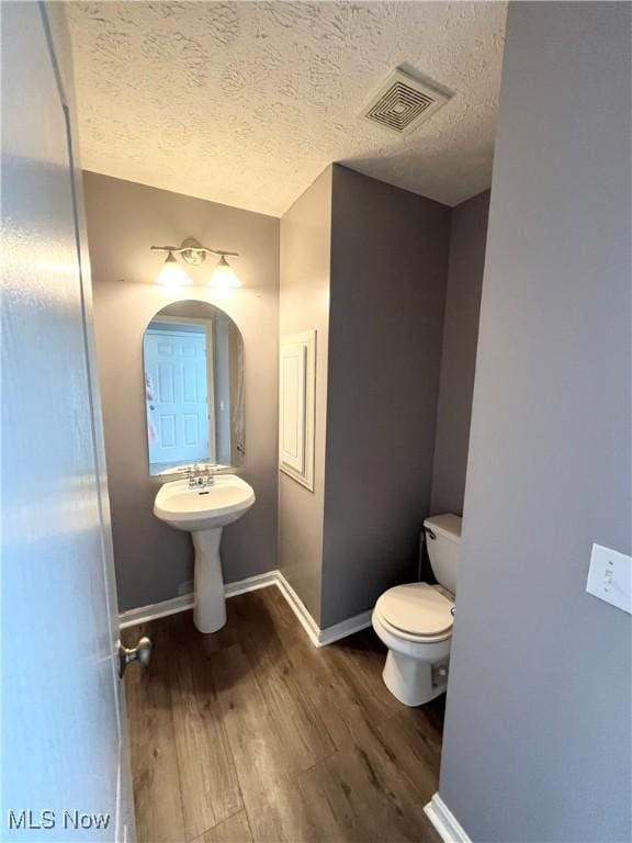 bathroom featuring a textured ceiling, wood-type flooring, and toilet