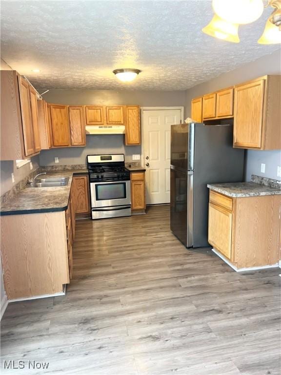 kitchen with sink, light wood-type flooring, a textured ceiling, and appliances with stainless steel finishes