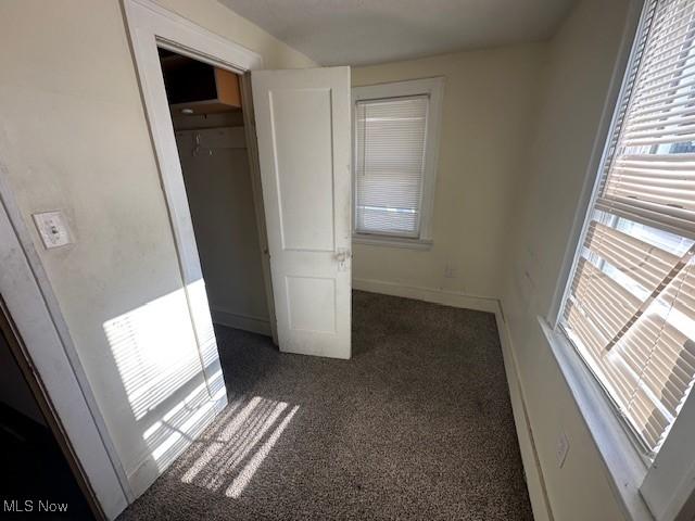 hall featuring dark colored carpet