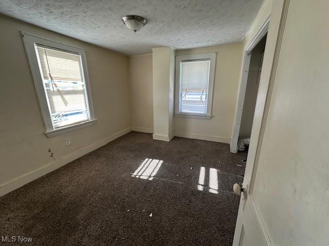 unfurnished bedroom with dark colored carpet and a textured ceiling