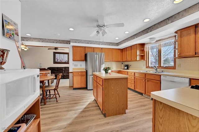 kitchen featuring white appliances, a center island, sink, and light hardwood / wood-style flooring