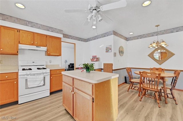 kitchen featuring light hardwood / wood-style flooring, gas range gas stove, ceiling fan, hanging light fixtures, and a kitchen island