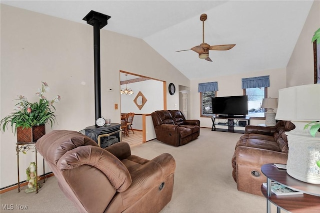 living room featuring light carpet, vaulted ceiling, ceiling fan, and a wood stove