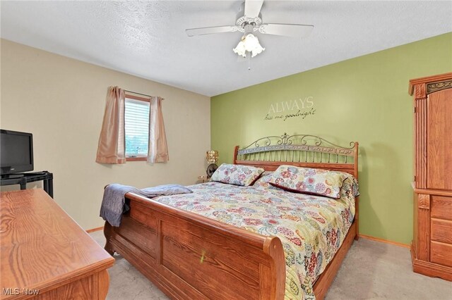 bedroom featuring ceiling fan, light colored carpet, and a textured ceiling