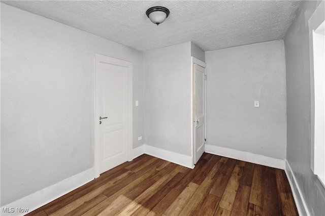 unfurnished room featuring dark hardwood / wood-style flooring and a textured ceiling