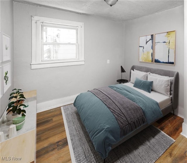 bedroom with dark hardwood / wood-style flooring and a textured ceiling