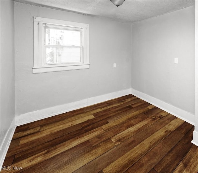 spare room with dark wood-type flooring and a textured ceiling