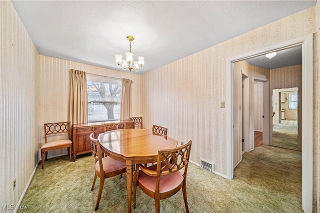 dining area featuring an inviting chandelier, carpet floors, and a textured ceiling