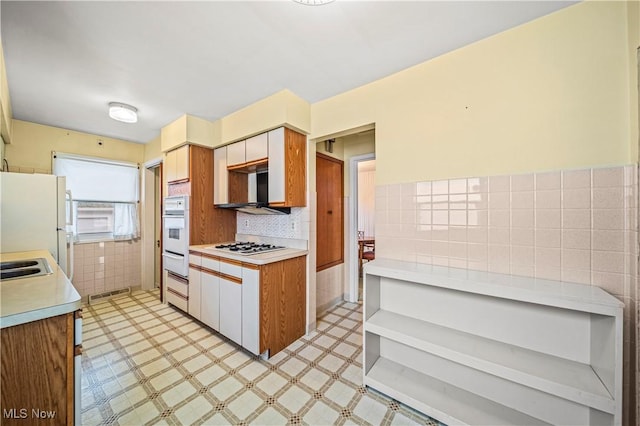 kitchen featuring sink, tile walls, and white appliances