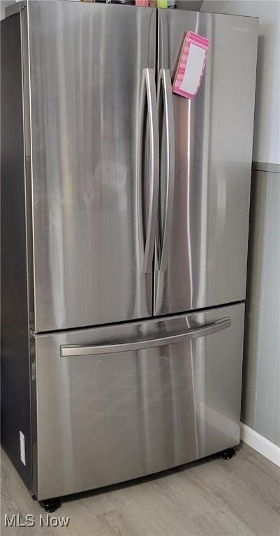 interior details with stainless steel refrigerator and light hardwood / wood-style floors