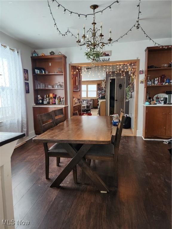 dining area with wood-type flooring and a notable chandelier