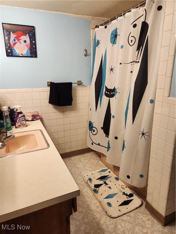 bathroom with tile walls, vanity, and a shower with shower curtain