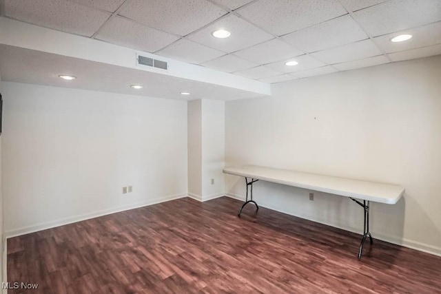 basement with a paneled ceiling and dark hardwood / wood-style floors