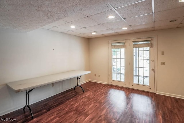 unfurnished office featuring a drop ceiling, recessed lighting, baseboards, and wood finished floors