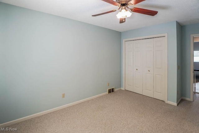 unfurnished bedroom featuring ceiling fan, a closet, and light carpet