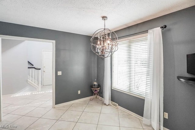 unfurnished dining area with a chandelier, a textured ceiling, and light tile patterned floors