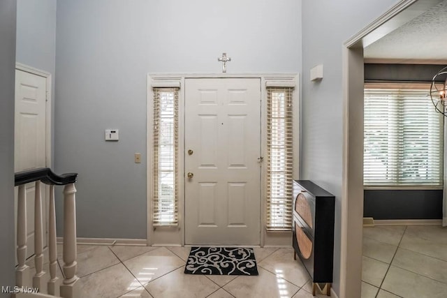 foyer entrance with light tile patterned floors and baseboards