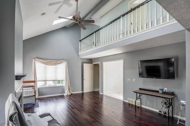 living area featuring a skylight, baseboards, ceiling fan, and wood finished floors