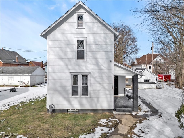 snow covered rear of property with a lawn