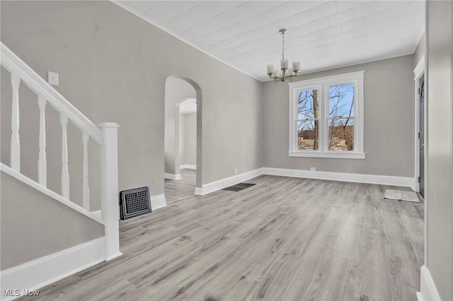 unfurnished living room featuring light hardwood / wood-style flooring, ornamental molding, and a chandelier