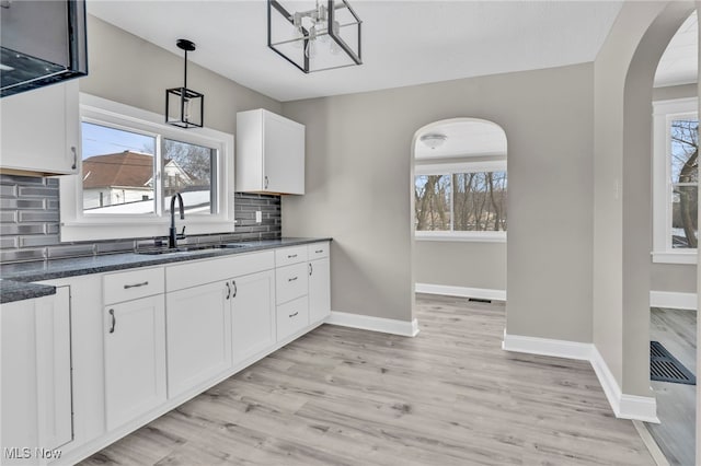 kitchen with pendant lighting, sink, light hardwood / wood-style flooring, white cabinetry, and tasteful backsplash